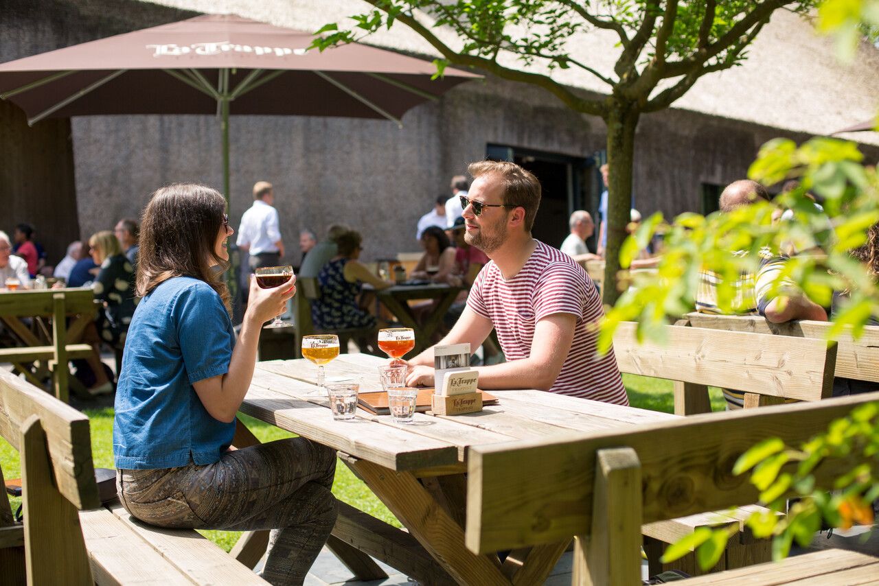 Twee mensen met een La Trappe biertje op het terras.