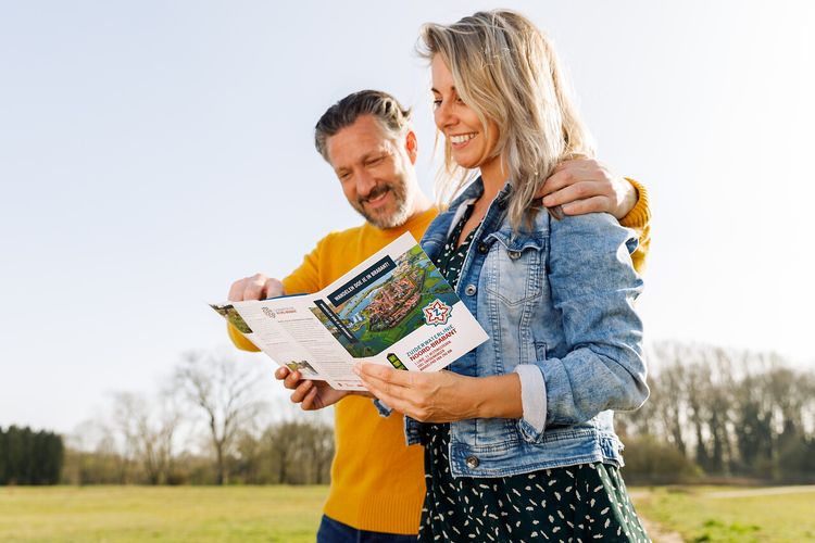 Twee wandelaars bekijken de zuiderwaterlinie wandelgids.
